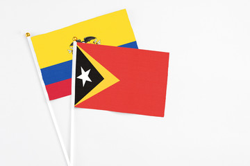 East Timor and Ecuador stick flags on white background. High quality fabric, miniature national flag. Peaceful global concept.White floor for copy space.
