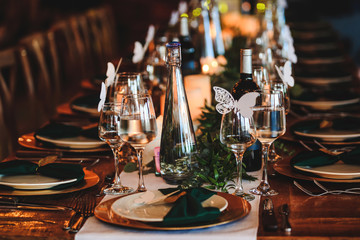 Dinner table setting. Banquet or holiday background in a rustic atmosphere.  Vintage decoration of reception table. Elegant arrangement of the holiday tableware. Wine glasses, plates, forks.