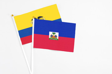 Haiti and Ecuador stick flags on white background. High quality fabric, miniature national flag. Peaceful global concept.White floor for copy space.