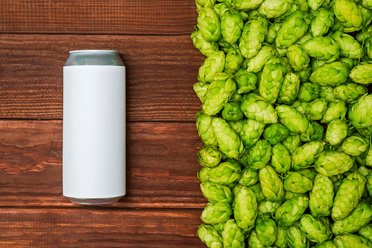 A Beer Can, Green Cones Of Hops On Wooden Background. Craft Canned Beer With Fresh Hops. Top View