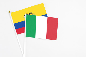 Italy and Ecuador stick flags on white background. High quality fabric, miniature national flag. Peaceful global concept.White floor for copy space.