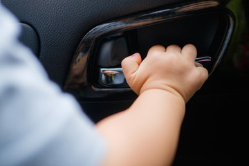 Little Asian 18 months / 1 year old baby boy child holding on to the door handle inside of the car, kid try to open the car door, Child safety concept / Shallow Dof / Selective focus
