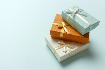 Small gift boxes are stacked on a pastel turquoise background. Christmas presents. Concept for celebration, carnival, party, festive sales. Winter season holidays empty banner with text space