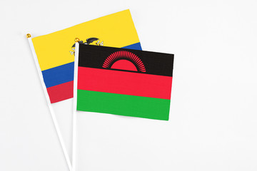 Malawi and Ecuador stick flags on white background. High quality fabric, miniature national flag. Peaceful global concept.White floor for copy space.