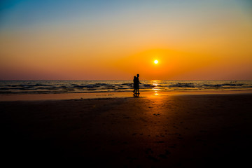 Fototapeta premium Siluate lovers and beach before sunset