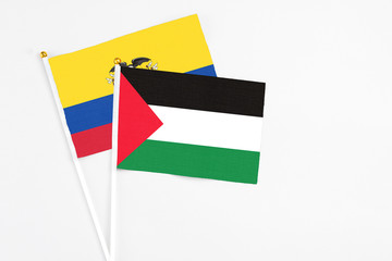 Palestine and Ecuador stick flags on white background. High quality fabric, miniature national flag. Peaceful global concept.White floor for copy space.