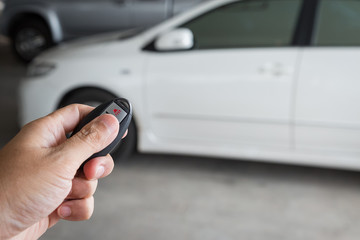 Hand holding car key remote at car park