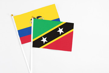 Saint Kitts And Nevis and Ecuador stick flags on white background. High quality fabric, miniature national flag. Peaceful global concept.White floor for copy space.