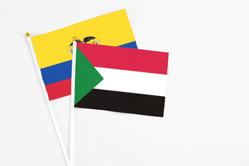 Sudan and Ecuador stick flags on white background. High quality fabric, miniature national flag. Peaceful global concept.White floor for copy space.