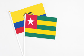Togo and Ecuador stick flags on white background. High quality fabric, miniature national flag. Peaceful global concept.White floor for copy space.