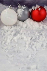 Fototapeta na wymiar Red White and Silver Christmas Ornaments on Snowy Backdrop with Copy Space