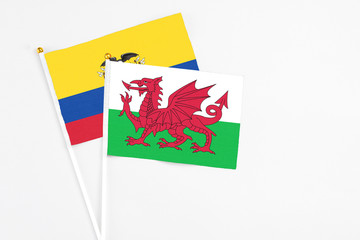 Wales and Ecuador stick flags on white background. High quality fabric, miniature national flag. Peaceful global concept.White floor for copy space.