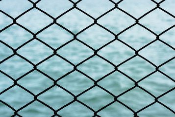 Grille iron fence with sea background. Concept of hinder/ protect freedom, peaceful life with strong wall.