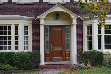 Fototapeta na wymiar Brick house with elegant wooden front door with sidelights and portico