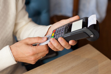 Young man paying for cafe by credit card reader