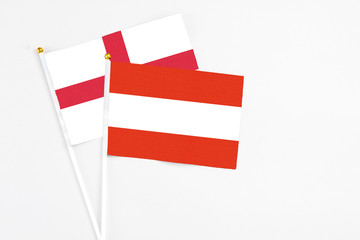 Austria and England stick flags on white background. High quality fabric, miniature national flag. Peaceful global concept.White floor for copy space.