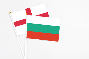Bulgaria and England stick flags on white background. High quality fabric, miniature national flag. Peaceful global concept.White floor for copy space.