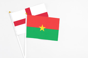 Burkina Faso and England stick flags on white background. High quality fabric, miniature national flag. Peaceful global concept.White floor for copy space.