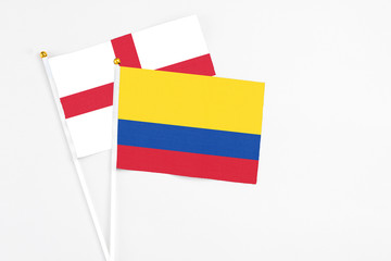 Colombia and England stick flags on white background. High quality fabric, miniature national flag. Peaceful global concept.White floor for copy space.