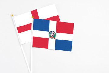 Dominican Republic and England stick flags on white background. High quality fabric, miniature national flag. Peaceful global concept.White floor for copy space.
