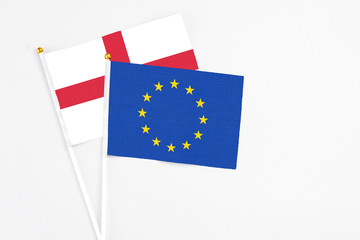 European Union and England stick flags on white background. High quality fabric, miniature national flag. Peaceful global concept.White floor for copy space.