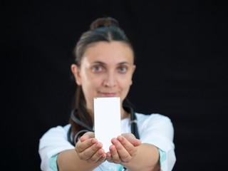 European woman doctor holding a box of medicines. Template for the design. Box mock up. Doctor's recommendation. Advertising of medicines. Black background.