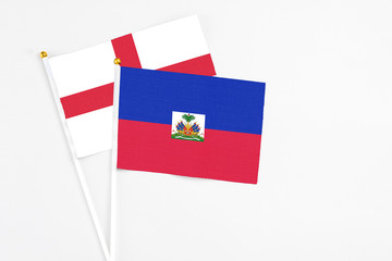 Haiti and England stick flags on white background. High quality fabric, miniature national flag. Peaceful global concept.White floor for copy space.