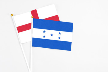 Honduras and England stick flags on white background. High quality fabric, miniature national flag. Peaceful global concept.White floor for copy space.