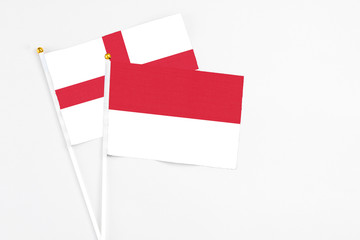 Indonesia and England stick flags on white background. High quality fabric, miniature national flag. Peaceful global concept.White floor for copy space.