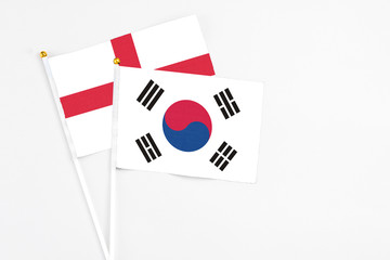 South Korea and England stick flags on white background. High quality fabric, miniature national flag. Peaceful global concept.White floor for copy space.
