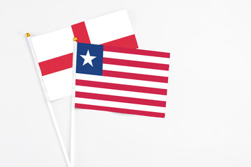 Liberia and England stick flags on white background. High quality fabric, miniature national flag. Peaceful global concept.White floor for copy space.