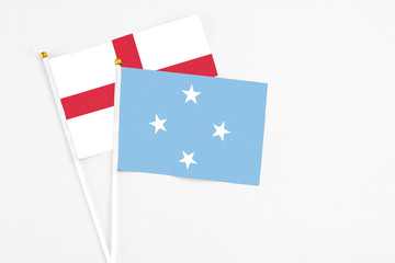 Micronesia and England stick flags on white background. High quality fabric, miniature national flag. Peaceful global concept.White floor for copy space.