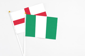 Nigeria and England stick flags on white background. High quality fabric, miniature national flag. Peaceful global concept.White floor for copy space.