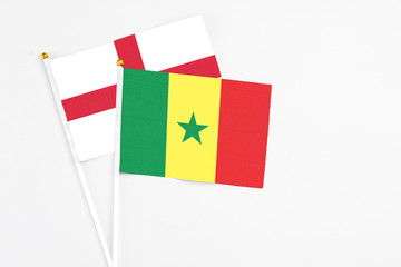 Senegal and England stick flags on white background. High quality fabric, miniature national flag. Peaceful global concept.White floor for copy space.
