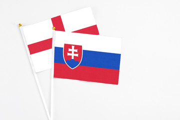 Slovakia and England stick flags on white background. High quality fabric, miniature national flag. Peaceful global concept.White floor for copy space.