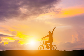 Silhouette of a Happy woman with bicycle playing with sunset background