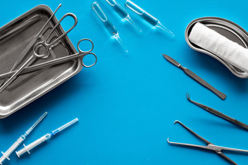 Plastic surgery instruments and tools with bandage on blue background top view frame copy space