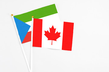 Canada and Equatorial Guinea stick flags on white background. High quality fabric, miniature national flag. Peaceful global concept.White floor for copy space.