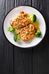 Amandine chicken fillet in almond sauce and broccoli close-up on a plate. Vertical top view