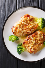 Amandine chicken with spicy almond sauce and broccoli close-up on a plate. Vertical top view