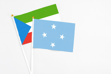 Micronesia and Equatorial Guinea stick flags on white background. High quality fabric, miniature national flag. Peaceful global concept.White floor for copy space.