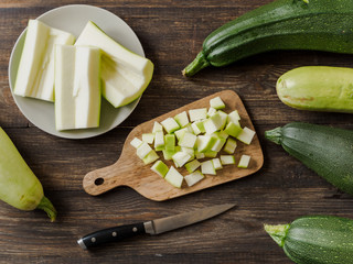 Zucchini harvest. Slices farm organic zucchini cubes for freezing on woodencutting board over brown...