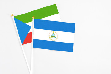 Nicaragua and Equatorial Guinea stick flags on white background. High quality fabric, miniature national flag. Peaceful global concept.White floor for copy space.