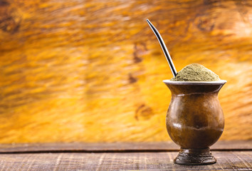 Yerba mate tea in wooden bowl on wooden table. Traditional drink from Brazil, Argentina, Paraguay and South America.