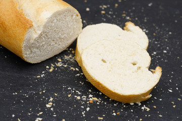 rustic crusty white bread lying on black slate in the kitchen