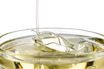 splash of yellow vegetable oil in a bowl on a white background