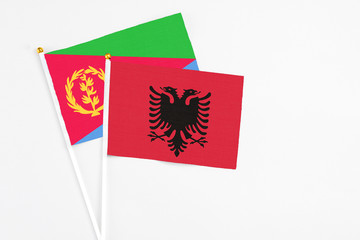 Albania and Eritrea stick flags on white background. High quality fabric, miniature national flag. Peaceful global concept.White floor for copy space.