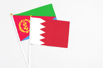 Bahrain and Eritrea stick flags on white background. High quality fabric, miniature national flag. Peaceful global concept.White floor for copy space.