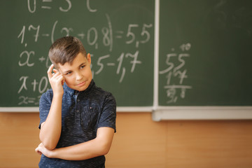 Cute boy stand in the classroom background of blackboard. Education. Elementary school