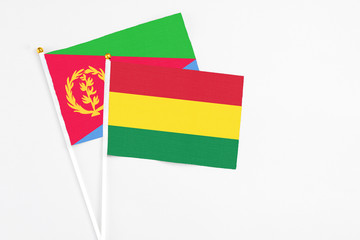 Bolivia and Eritrea stick flags on white background. High quality fabric, miniature national flag. Peaceful global concept.White floor for copy space.